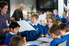 Teacher handing out paper to a group of school pupils