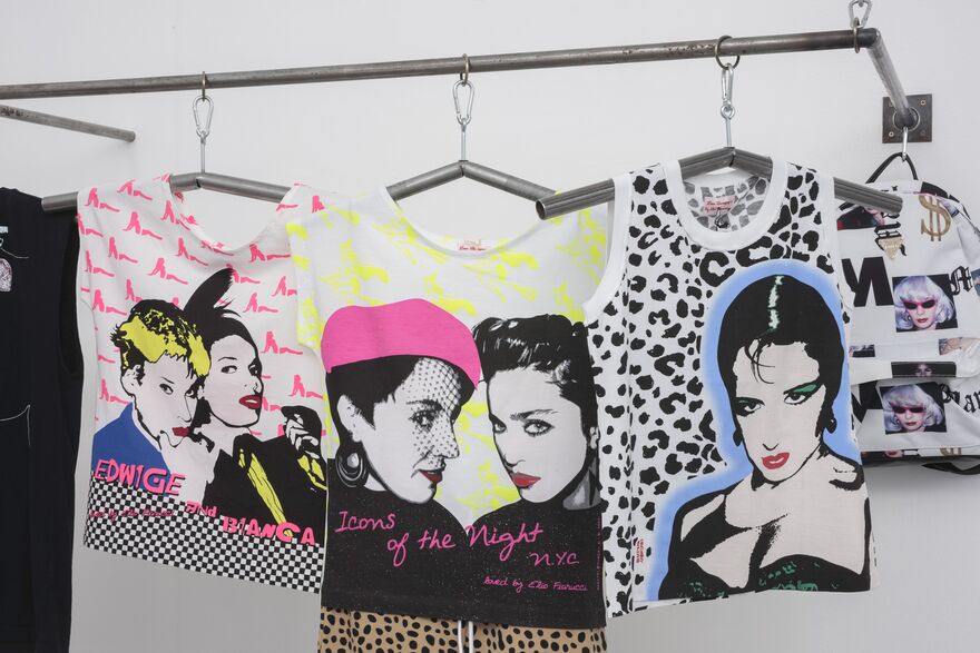 A close-up shot of 3 t-shirts which hang on a rack in DCA Galleries as part of 'Spring / Summer 2015' exhibition. They are neon and have pictures of Maripol on them.