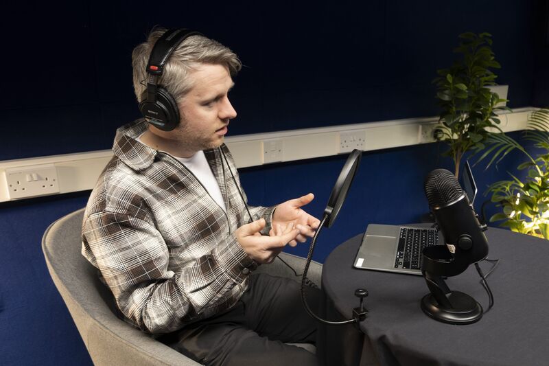 A person records a podcast in DCA's media suite.